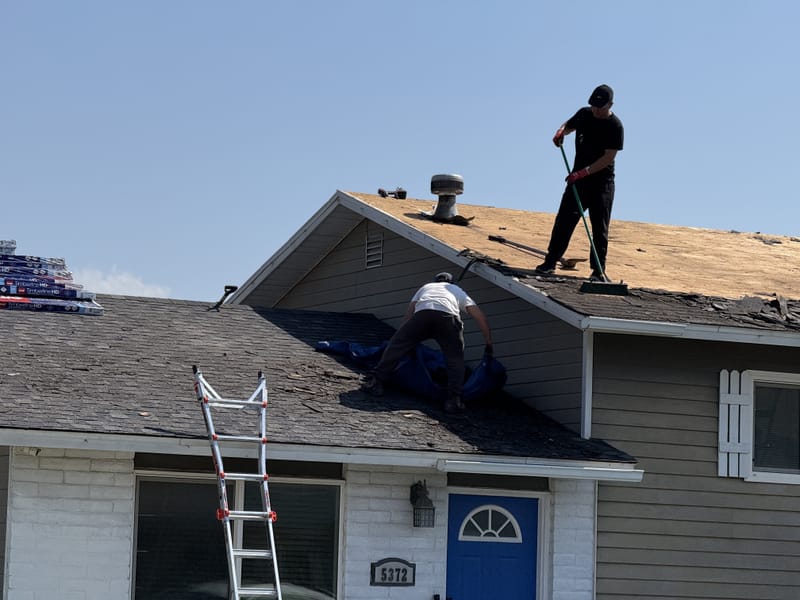 Worker placing first solar panel on bare roof deck during installation