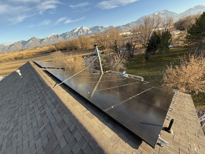 [Tier 1 Trina panels] Sideways shot of ground-mounted solar array with racking structure and residential property in background