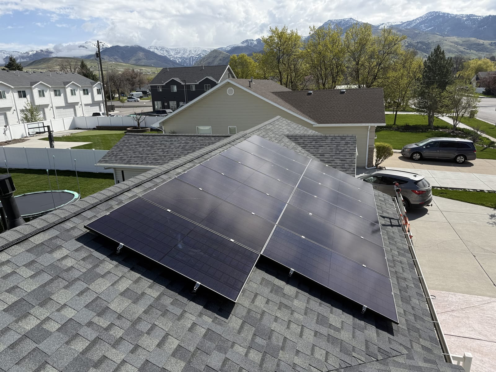 [black-on-black panels] Roof-level view of solar panels with driveway and street below