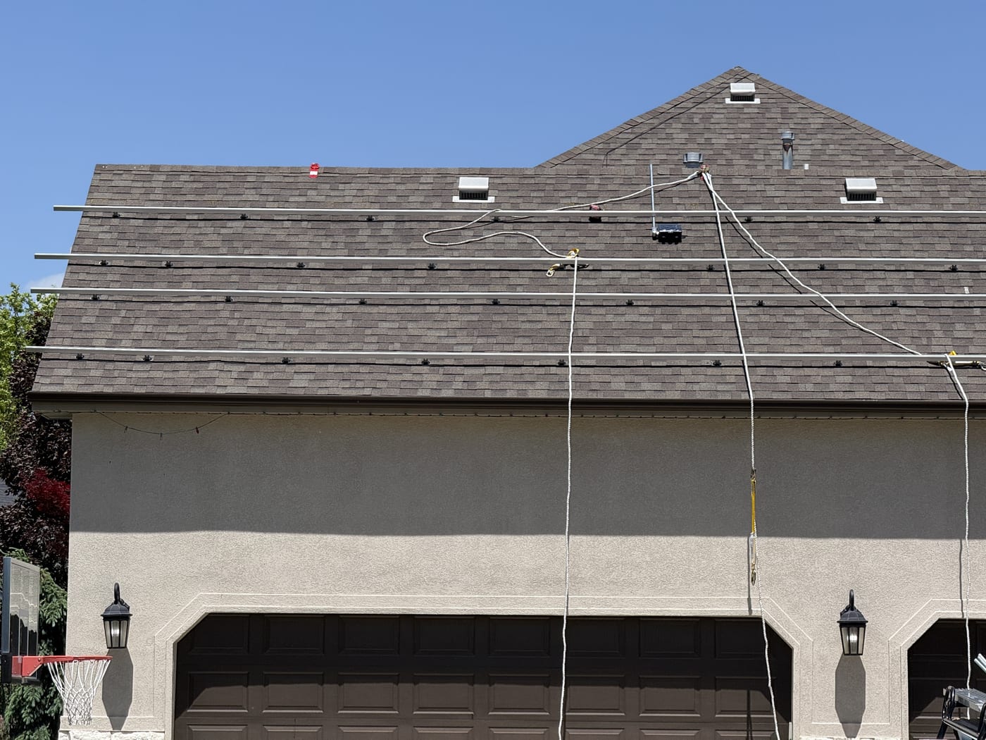 House exterior showing roof with racking mounts installed and wiring visible above garage