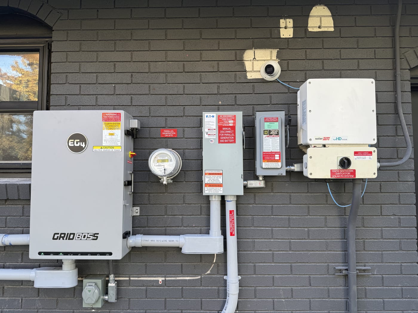Close-up of EG4 GridBOSS inverter meter and disconnect equipment on dark brick exterior