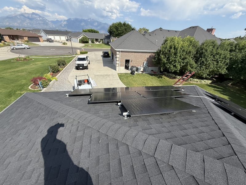 Solar panels on roof looking down to residential neighborhood with work truck and houses below