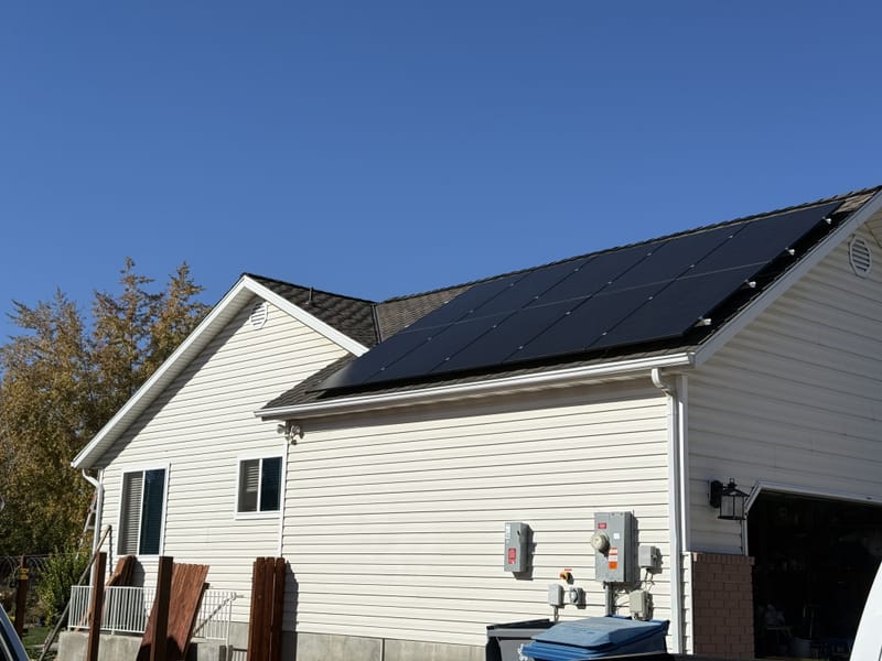 [Trina panels] House exterior showing completed solar array on front roof with conduit to meter and disconnect on siding