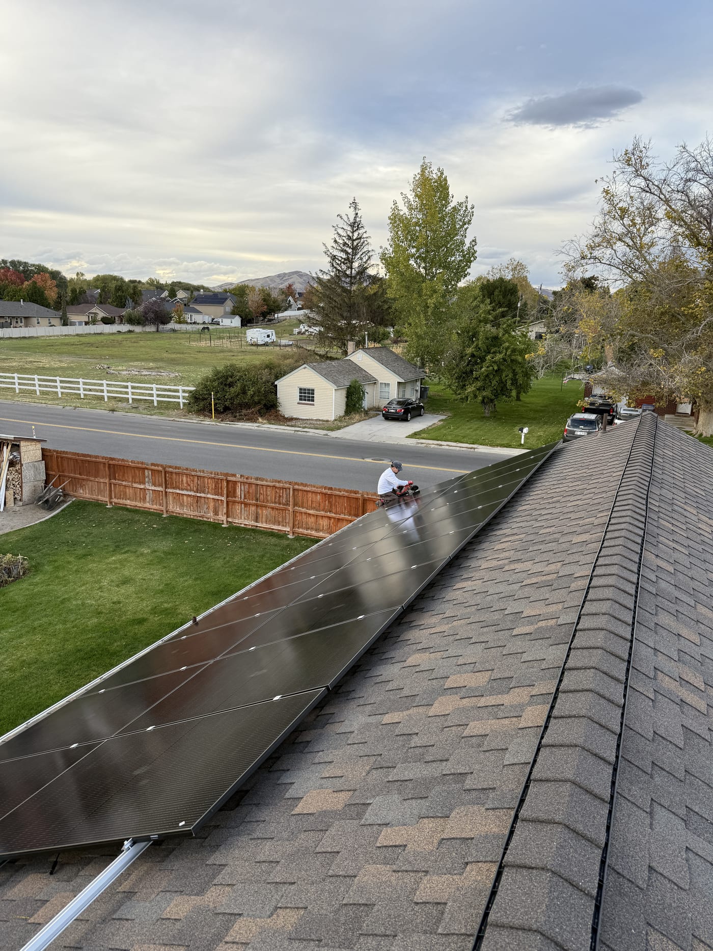 [Trina panels] Completed solar panels on roof edge looking down to backyard with fence and neighborhood