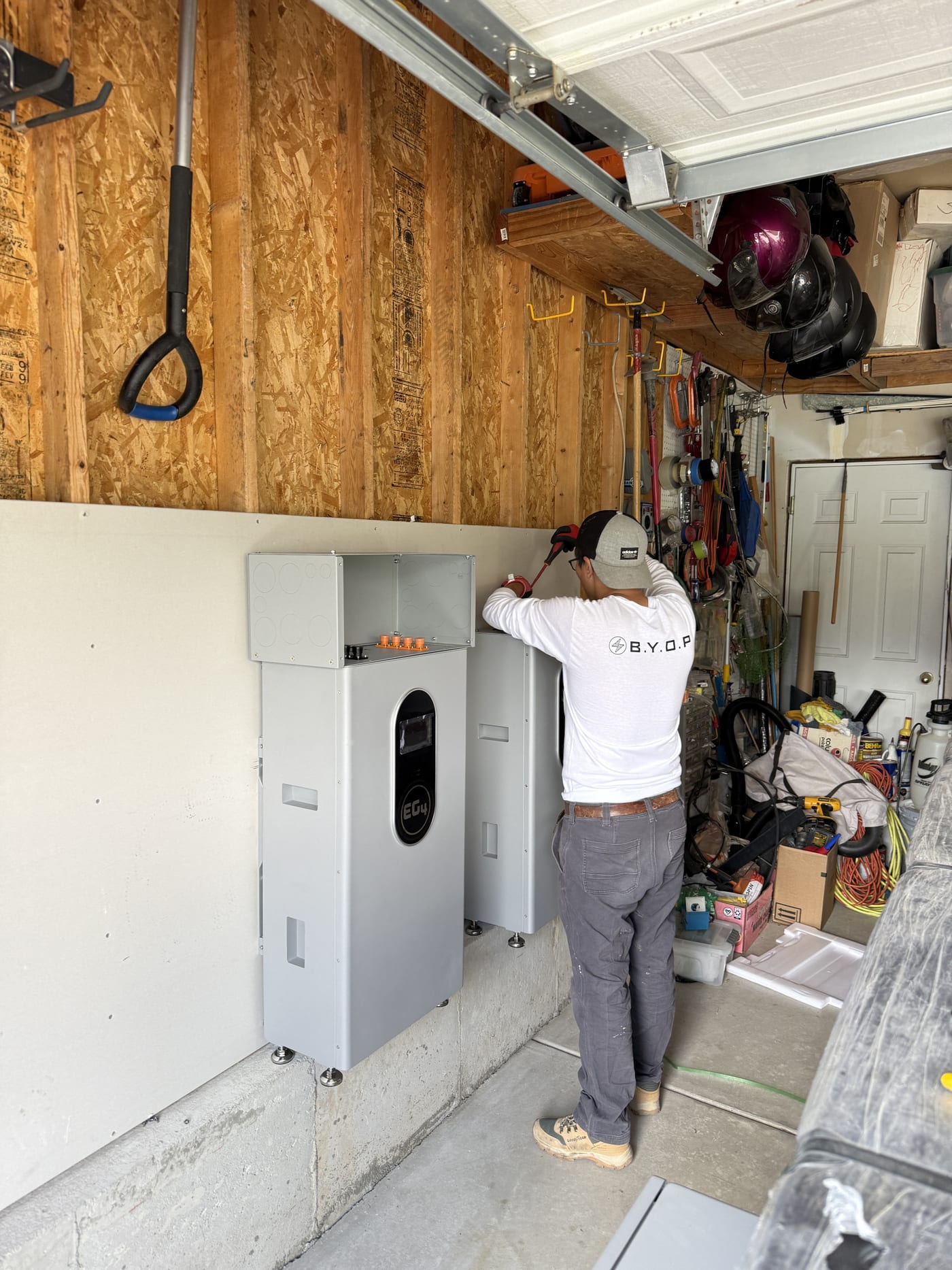 BYOP crew member mounting EG4 equipment on garage wall during battery system installation