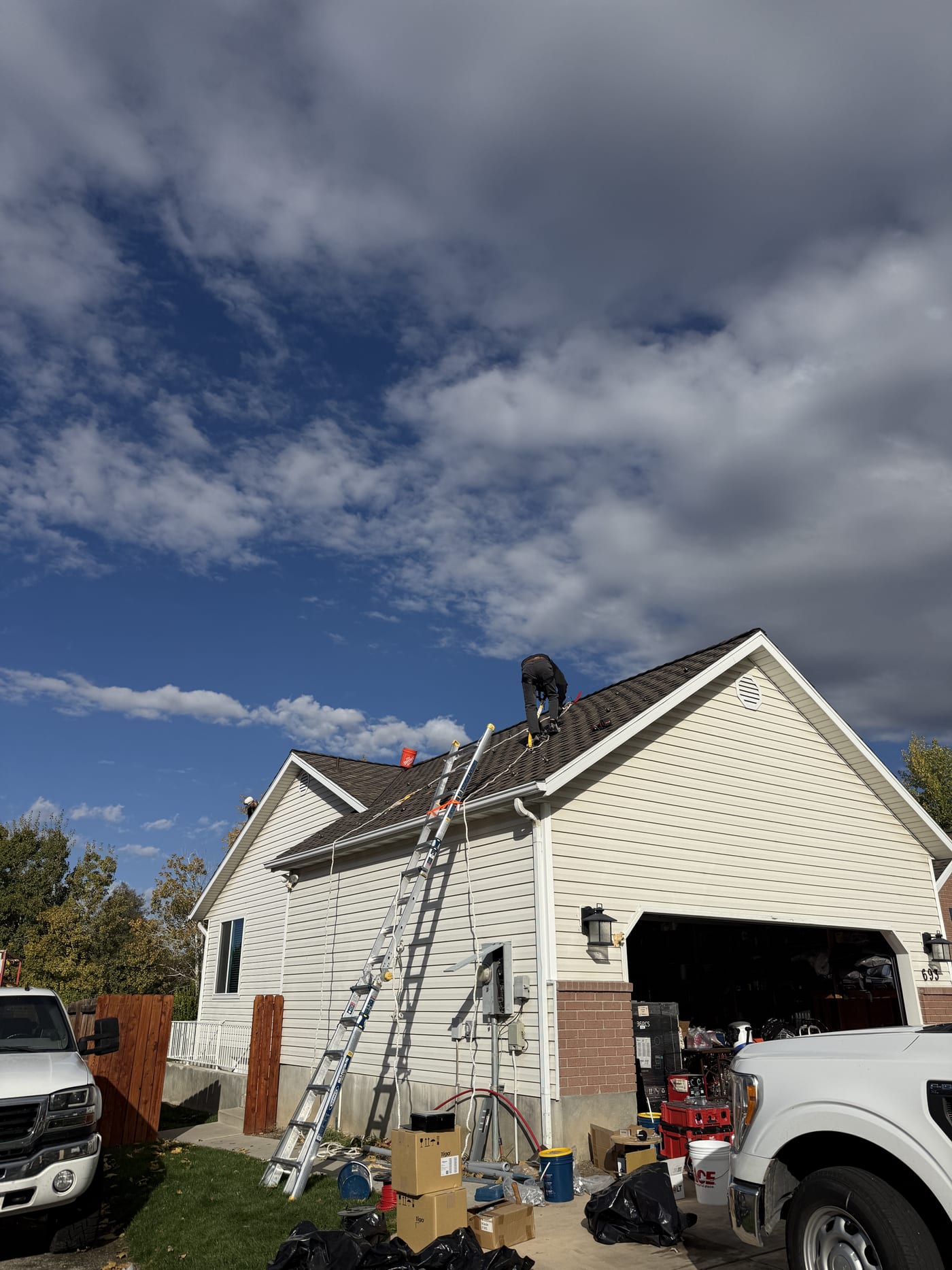 House exterior with equipment and ladders staged in driveway on cloudy day before installation