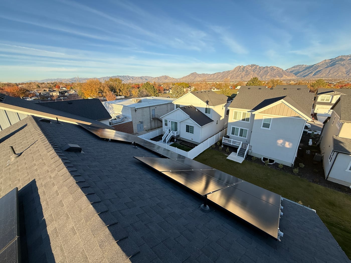 [Tier 1 Trina panels] Solar panels across roof planes with dramatic Wasatch mountain range and blue sky panorama
