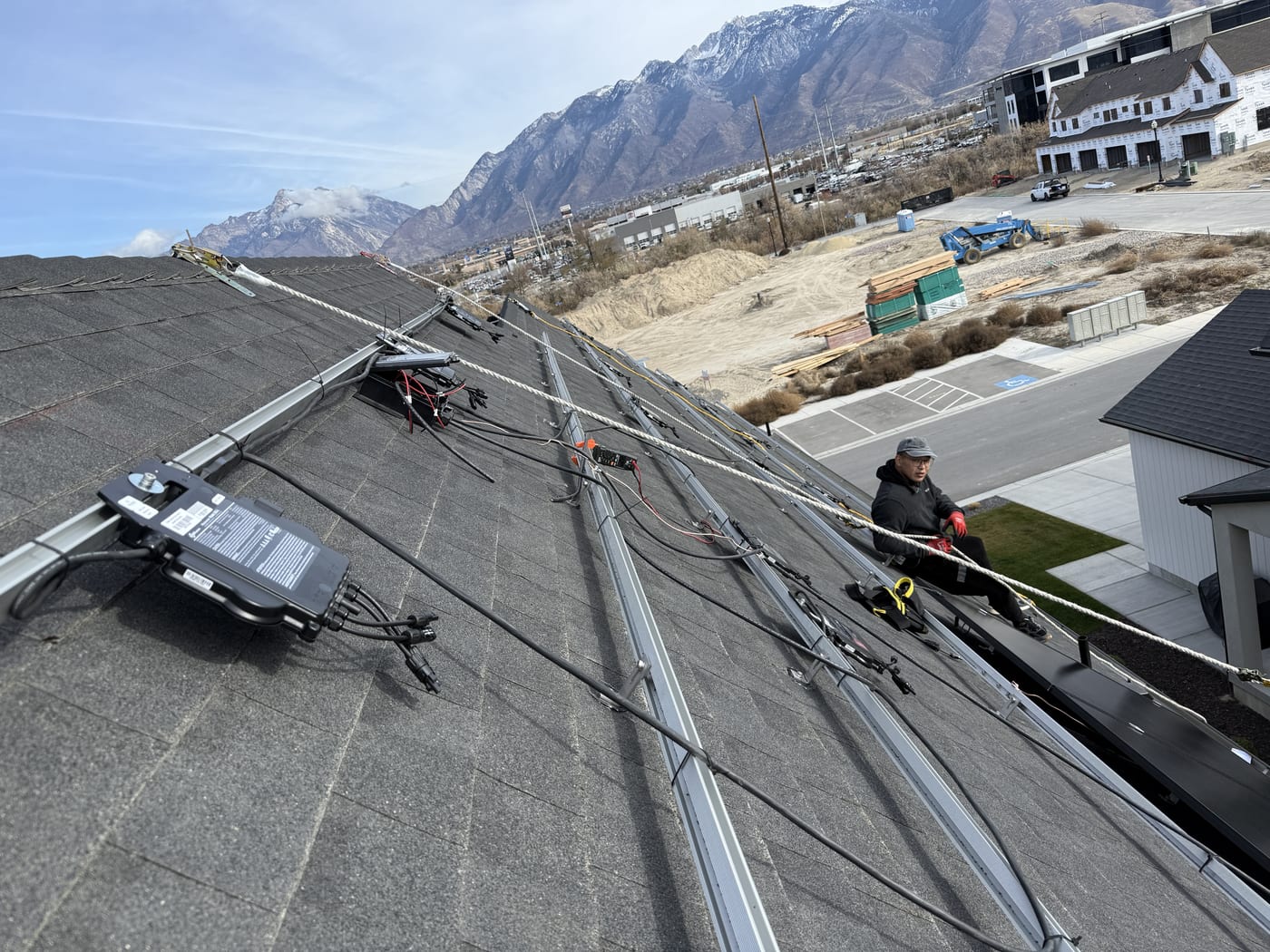 On-roof shot of crew working with microinverters and racking, wiring connections visible, mountain views