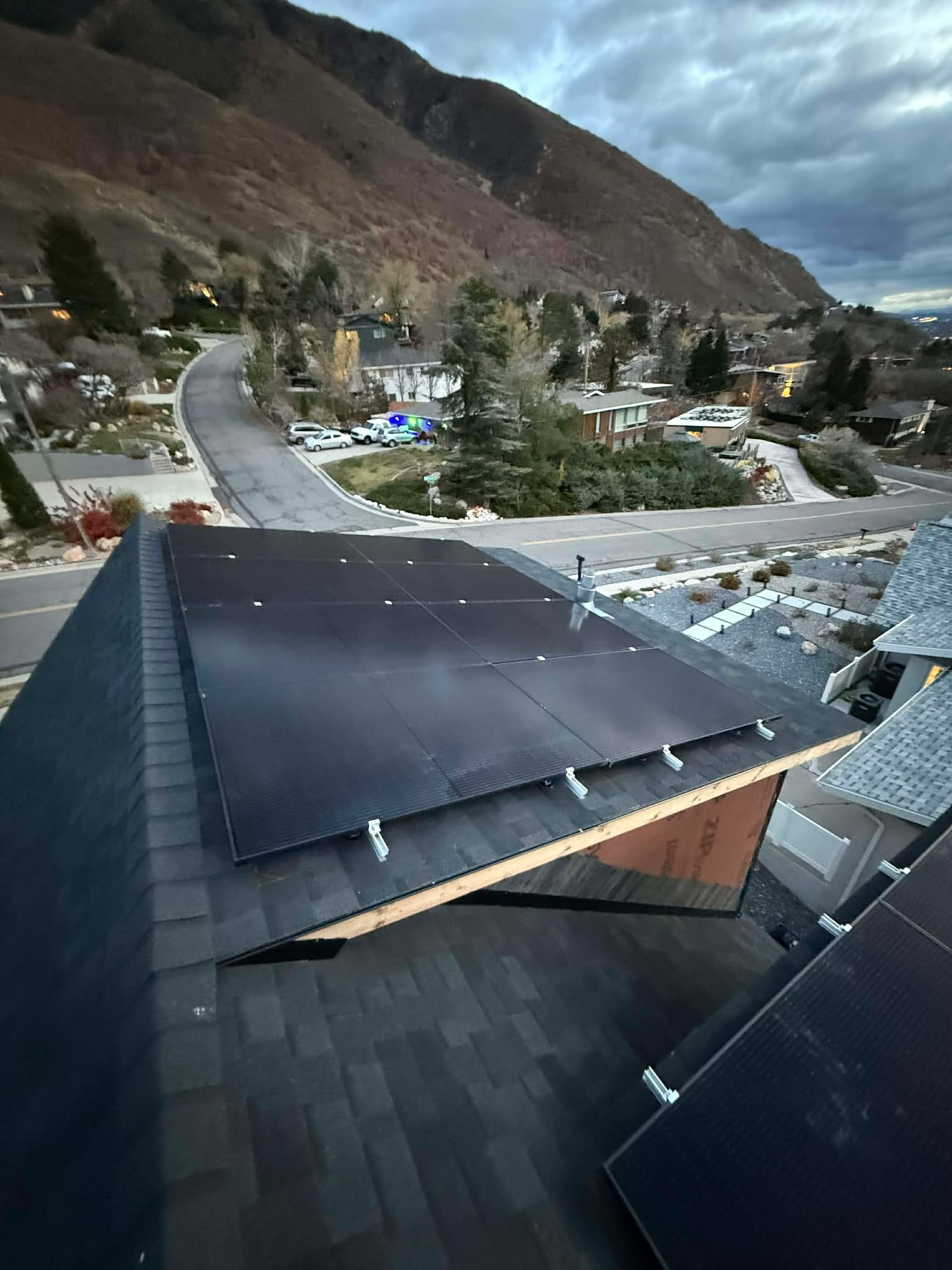 Solar panels on multi-plane roof overlooking Millcreek neighborhood and canyon, dramatic clouds and mountains