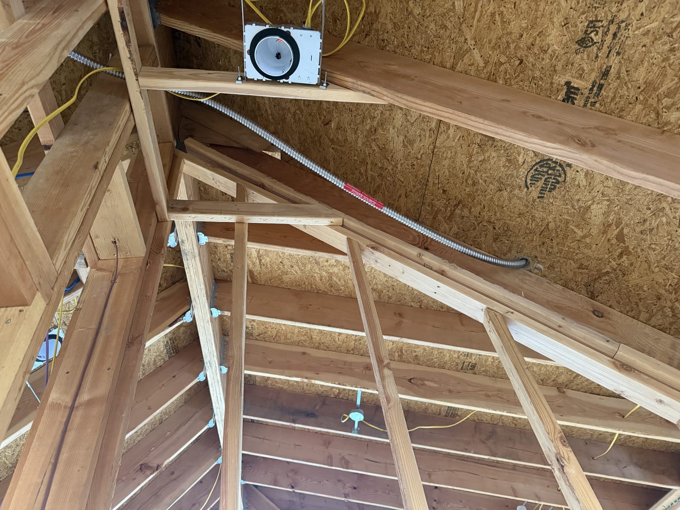 MC4 conduit with Warning Photovoltaic Power Source label running through attic rafters in new construction