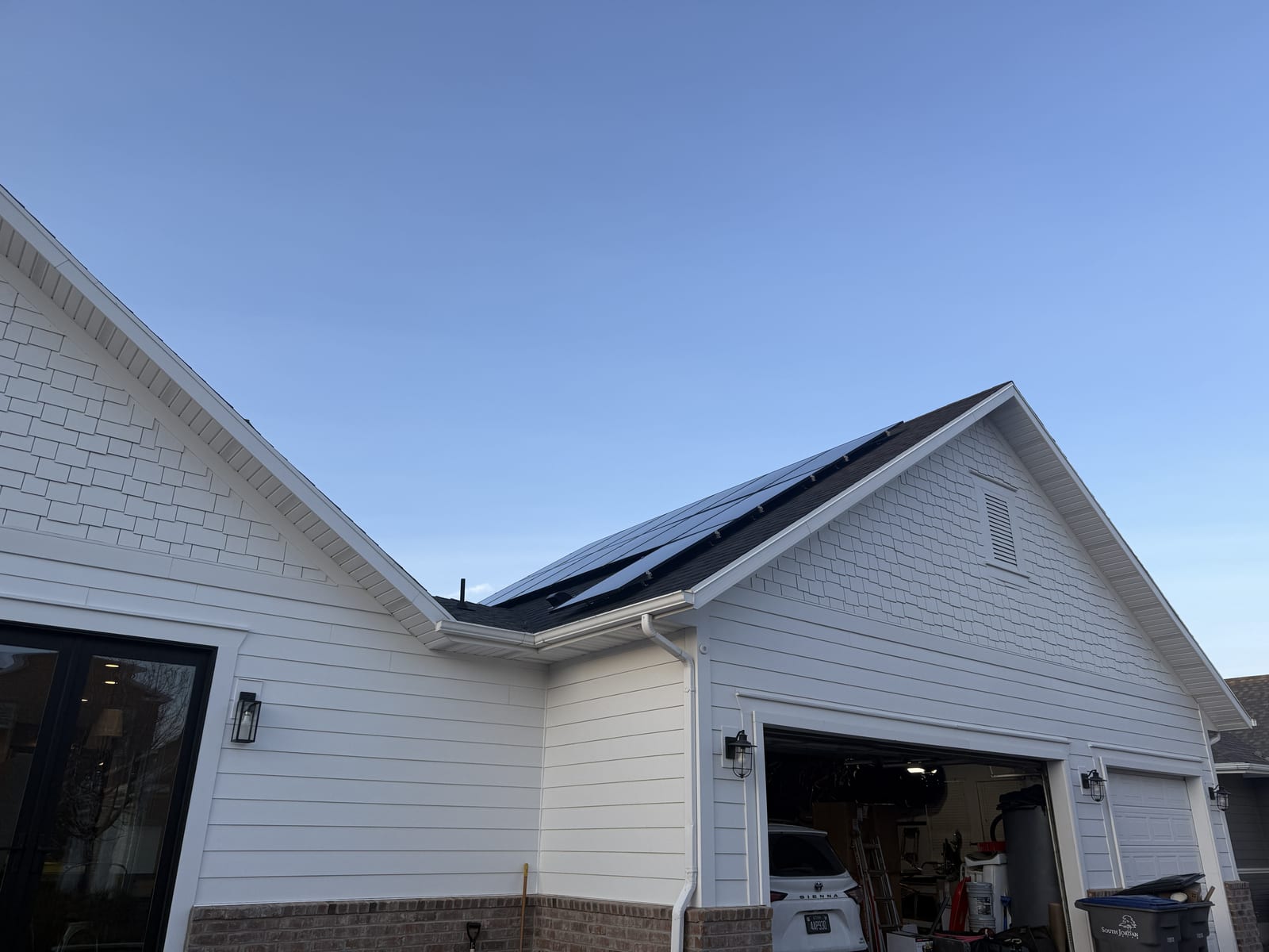 [Trina panels] Side view of house showing solar panels on roof section, rotated image, blue sky
