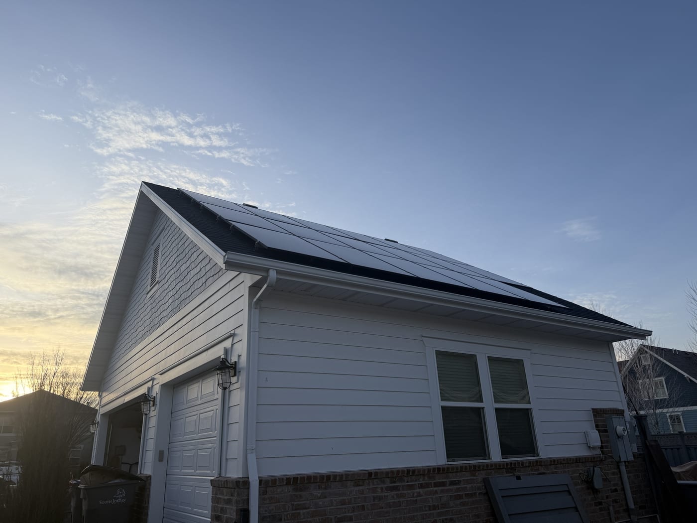 [Trina panels] House exterior showing solar panels on roof, sunset light, rotated image